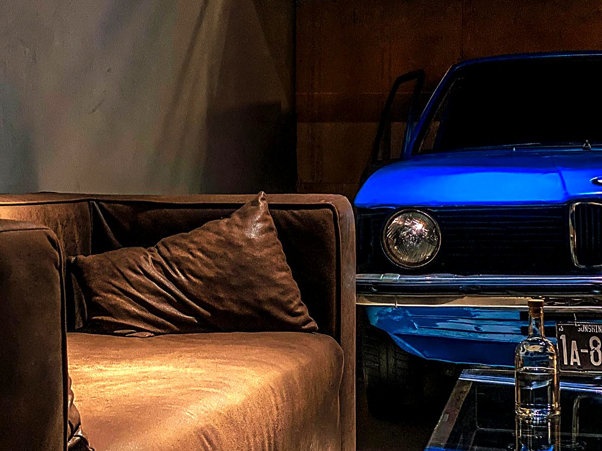 Интерьер зала Гараж — кожаный диван и синяя BMW
